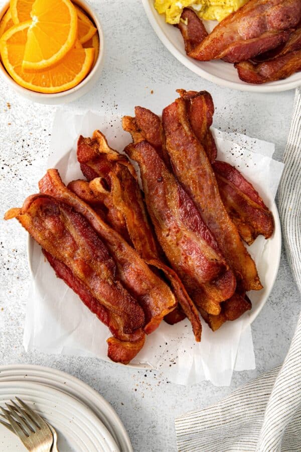 Air fryer bacon slices on a serving plate on tabletop.