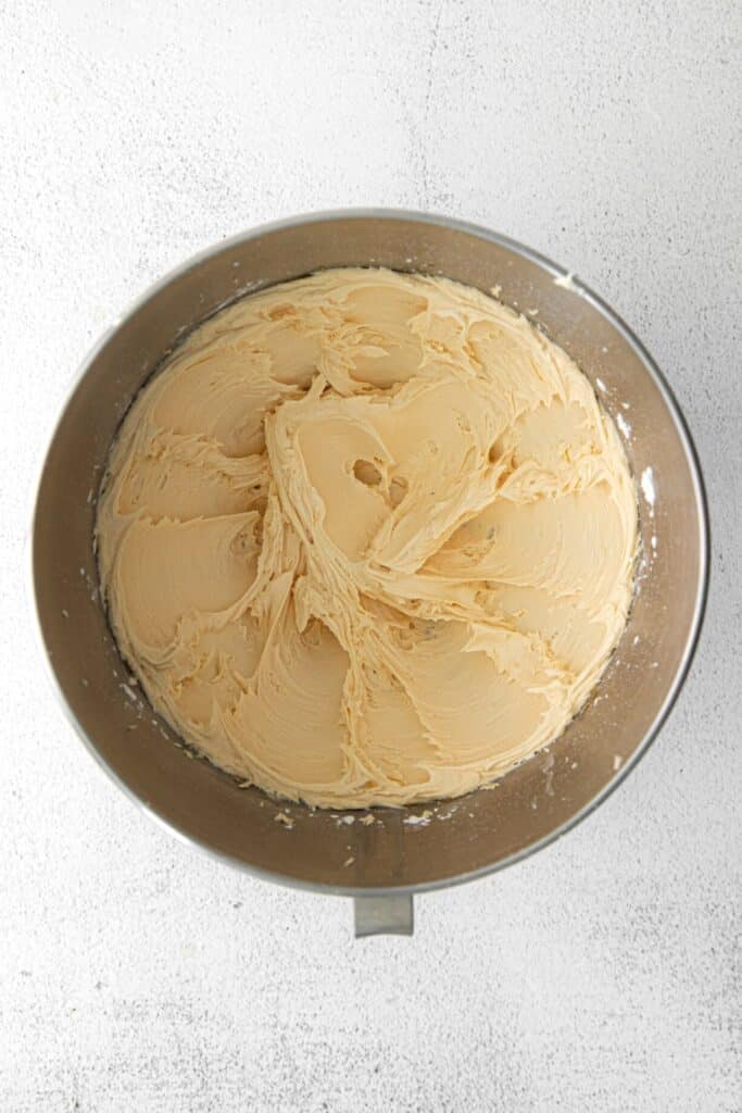 Caramel buttercream frosting in the metal bowl of a stand mixer.