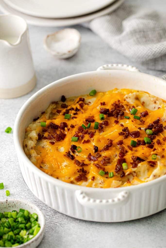 Twice baked potato casserole with melted cheese, bacon bits and green onions on top.