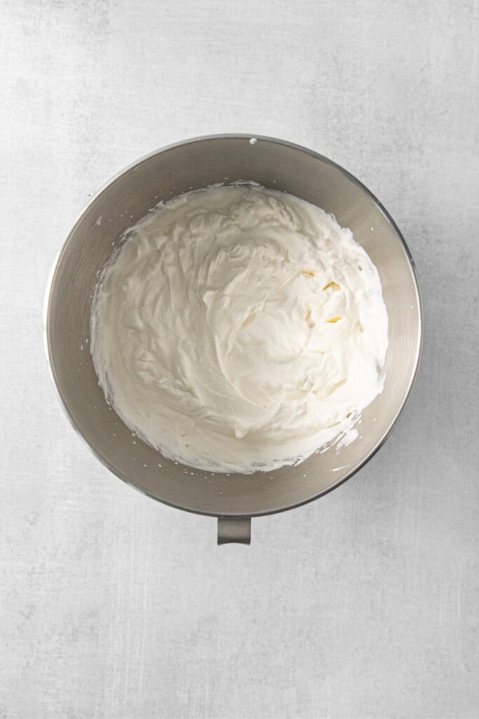 Freshly-whipped vanilla whipped cream in a stainless-steel mixing bowl.