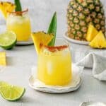 Pineapple Margarita in a cocktail glass rimmed with Tajin and garnished with a pineapple wedge.