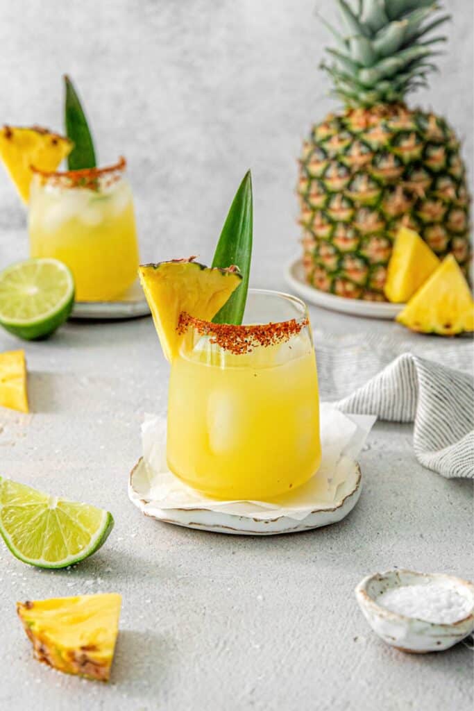 Pineapple Margarita in a cocktail glass rimmed with Tajin and garnished with a pineapple wedge.
