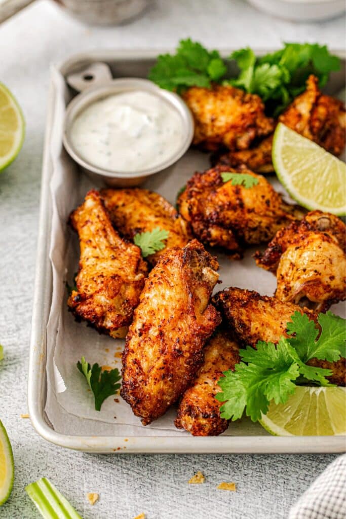 Tequila lime wings on a small metal tray with a ramekin of tequila-lime dipping sauce.
