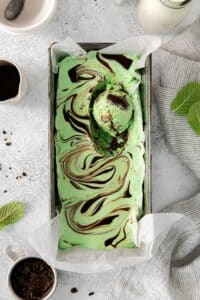 No-churn mint chocolate chip ice cream with hot fudge topping swirled over the surface.