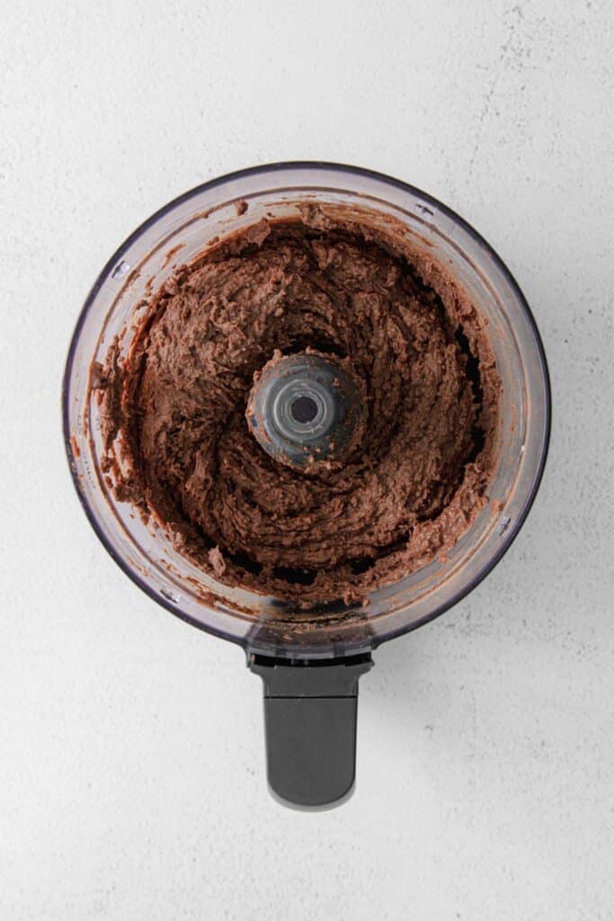 Smooth and creamy dark chocolate hummus in the bowl of a food processor.