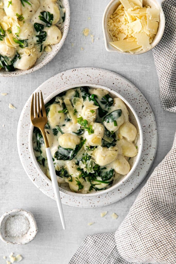 A serving of spinach gnocchi with parmesan cheese.