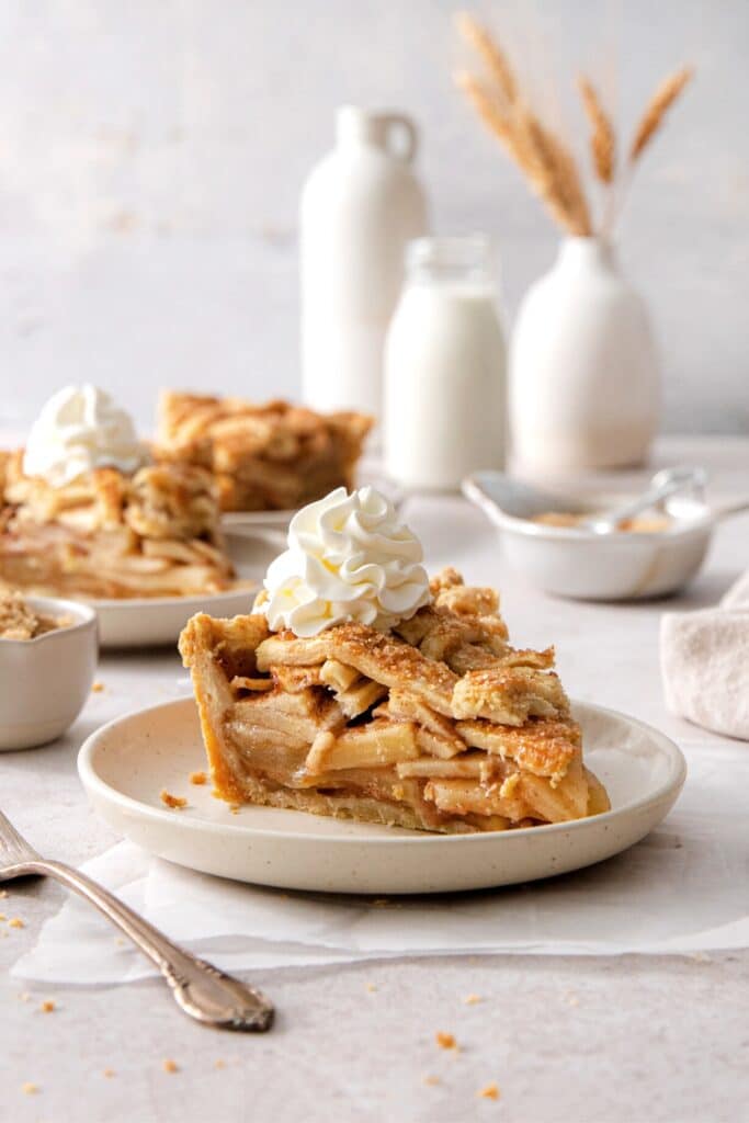 A slice of Grandma's apple pie topped with a dollop of whipped cream.