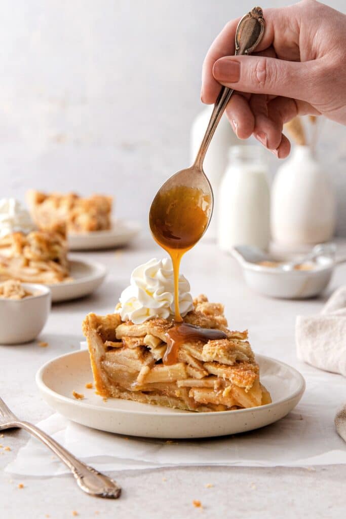 Slice of Grandma's apple pie topped with whipped cream and salted caramel sauce.
