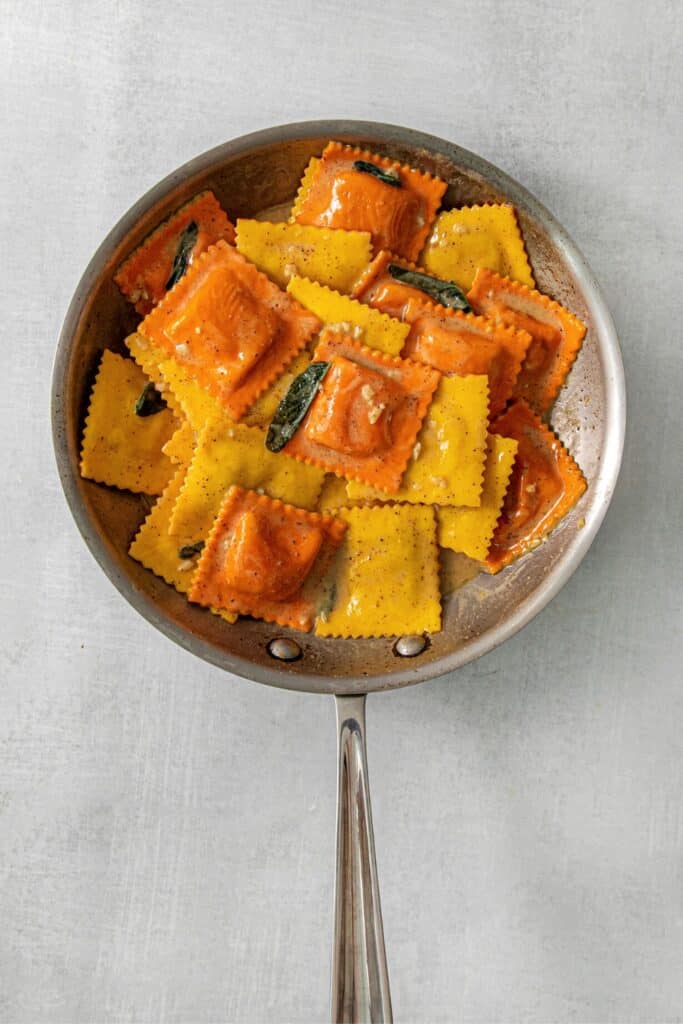 Butternut squash ravioli in a skillet with brown-butter sage sauce.