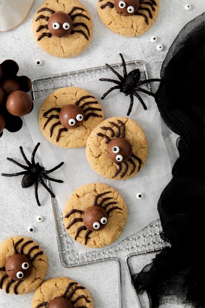 An overhead view of peanut butter spider cookies on a Halloween dessert table.
