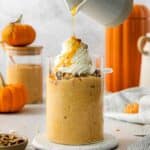 Pumpkin pie overnight oats served for breakfast in a glass cup with chopped pecans and whipped cream.