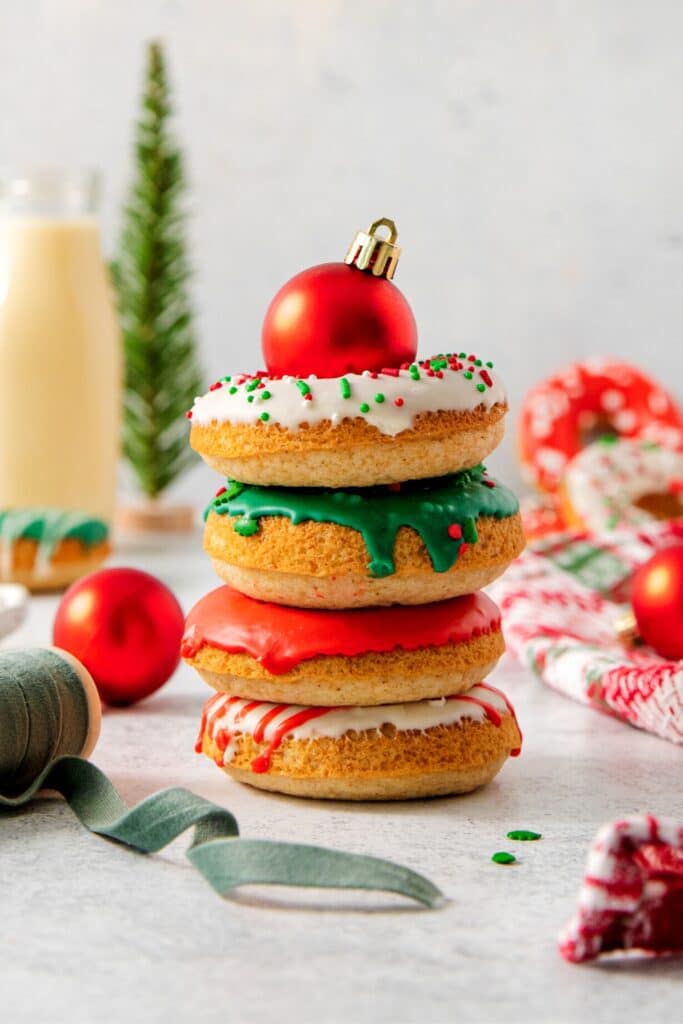 A stack of 4 glazed and decorated Christmas donuts.