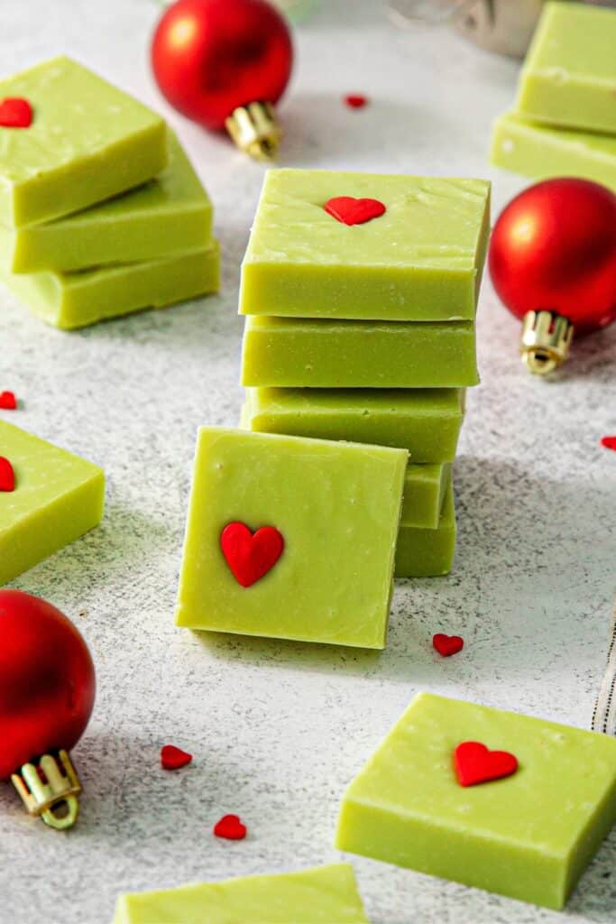 Stacked squares of Grinch Christmas Fudge on a holiday dessert table.
