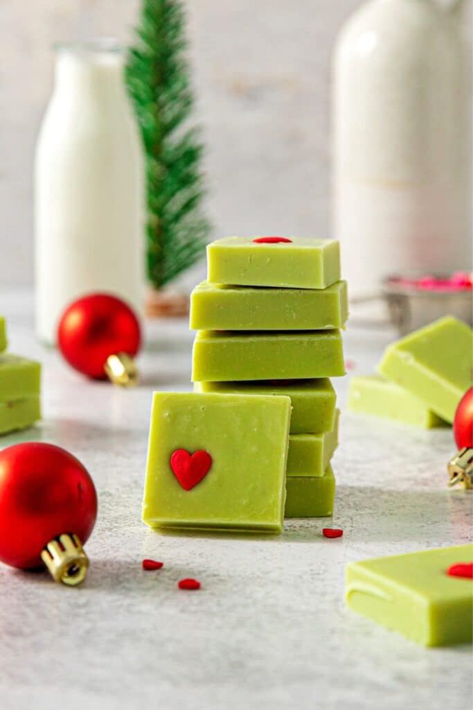 A stack of Grinch desserts next to a glass bottle of milk.