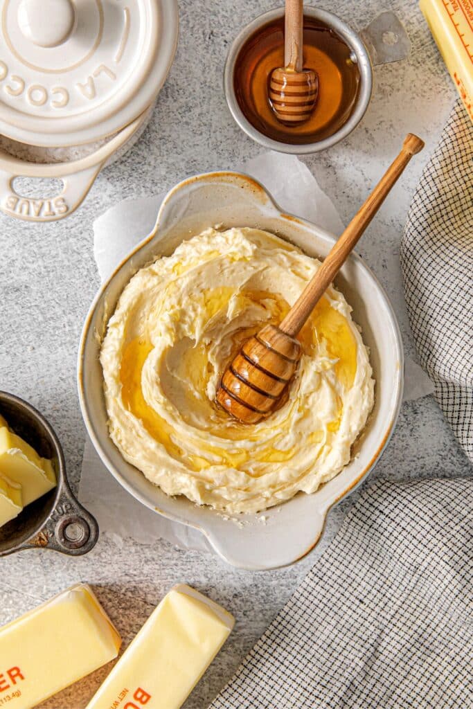 Whipped honey butter in a ramekin with swirls of honey drizzled on top.