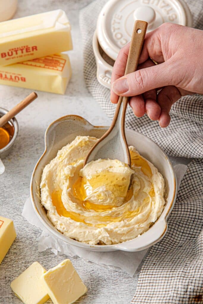 Whipped honey butter spread being spooned from a ramekin on a serving table.