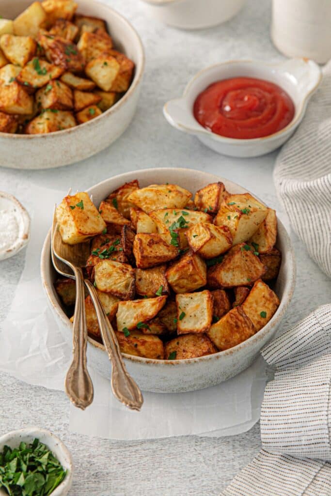 Crispy air fryer breakfast potatoes served with a side of ketchup and flaky salt.