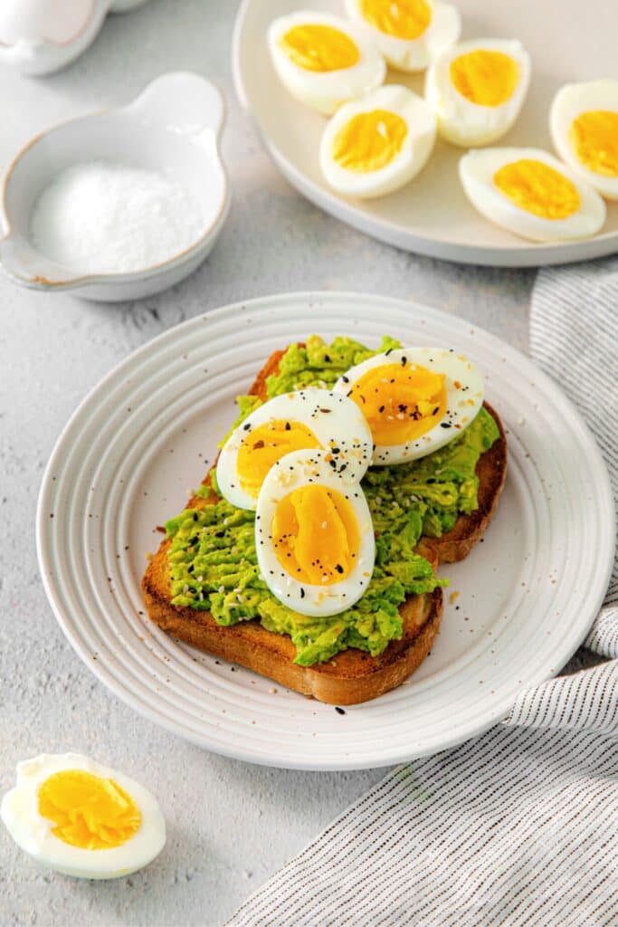 Soft boiled eggs cut in half and plated over avocado toast.