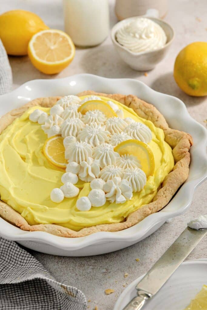 Lemon pie decorated with fresh lemon slices and piped-on whipped cream.