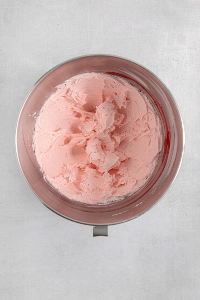 Pink frosting in a metal bowl.