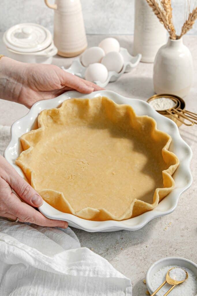 A shortbread pie crust fluted within a ceramic pie dish.