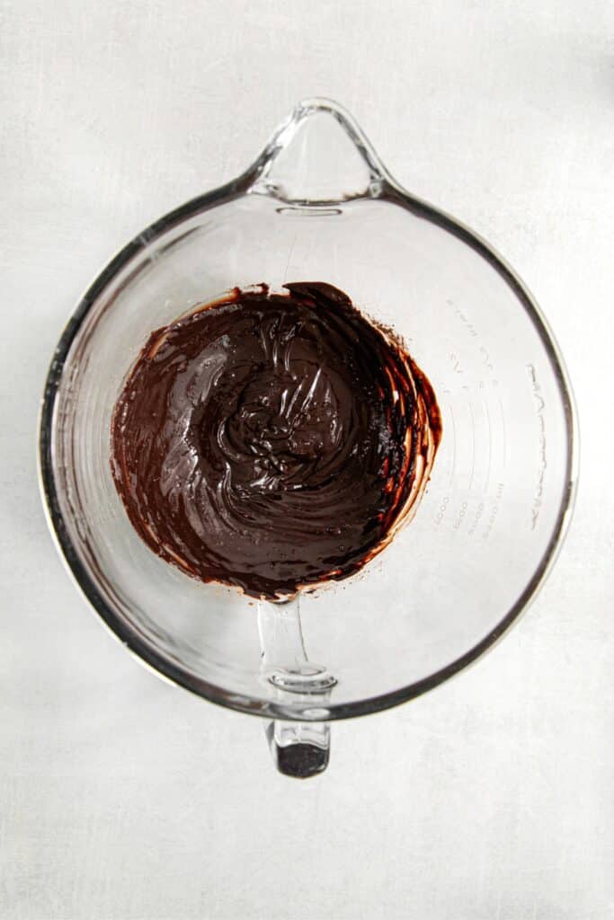 A mixture of cocoa and melted butter in a glass mixing bowl.