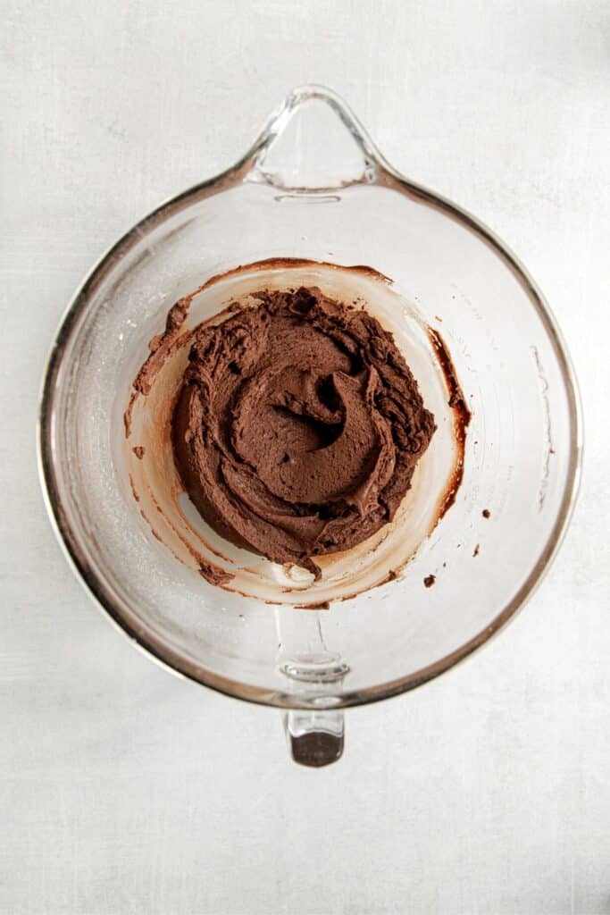 Brownie frosting in a glass batter bowl.