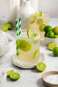 The best classic Margarita on the rocks in a salt-rimmed glass garnished with wheels of lime.